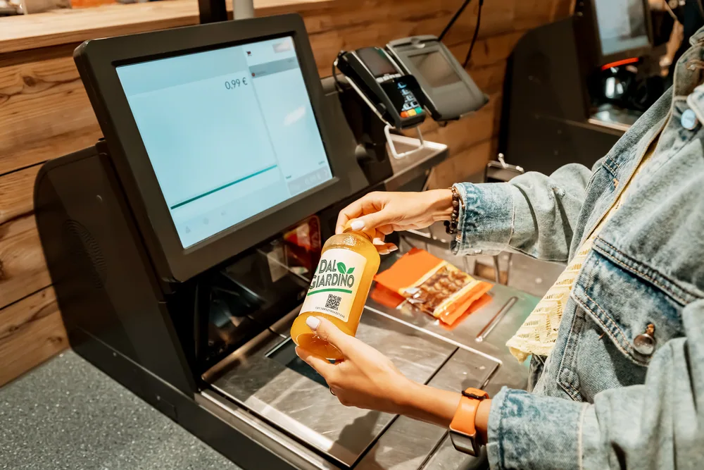 Consumator scanând codul QR al unui produs la self-checkout